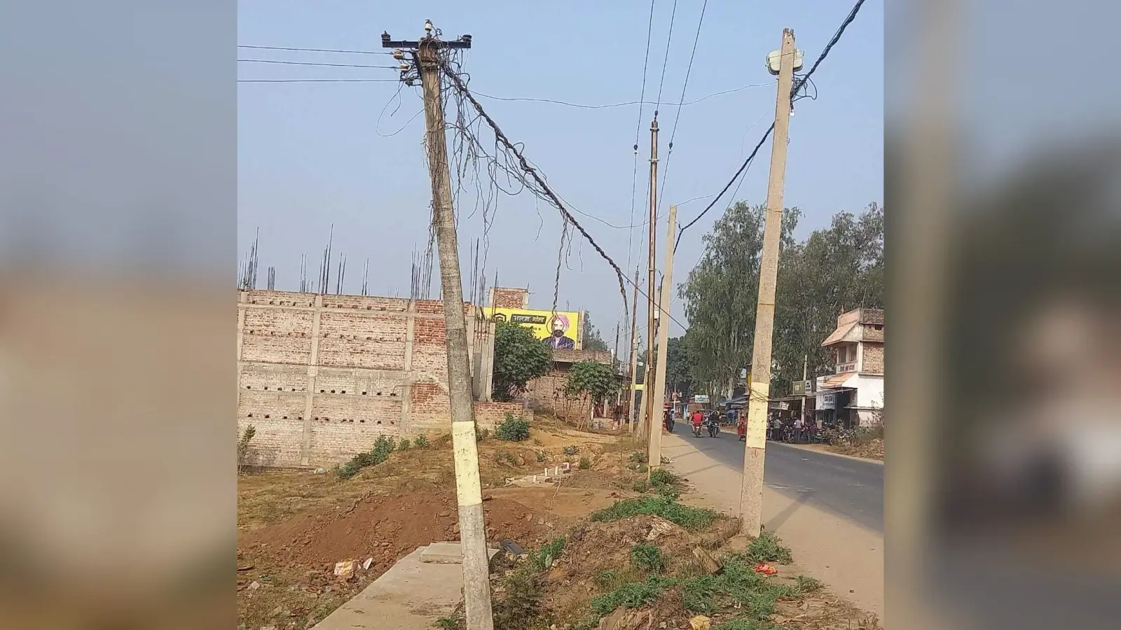 सड़क किनारे झुका बीजली का पोल