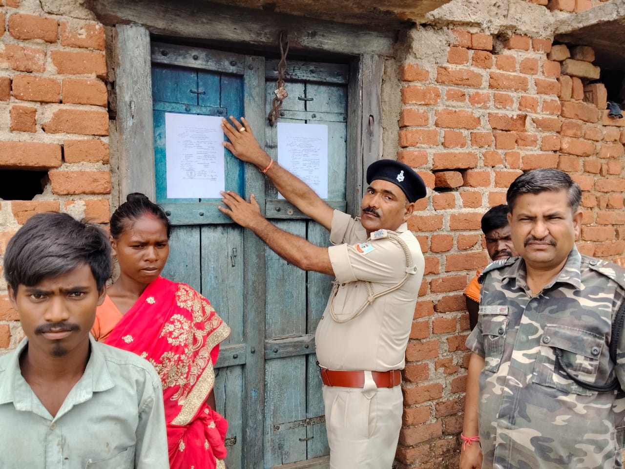 फरार अभियुक्तों के घर न्यायालय के निर्देश पर चिपकाया गया इश्तेहार