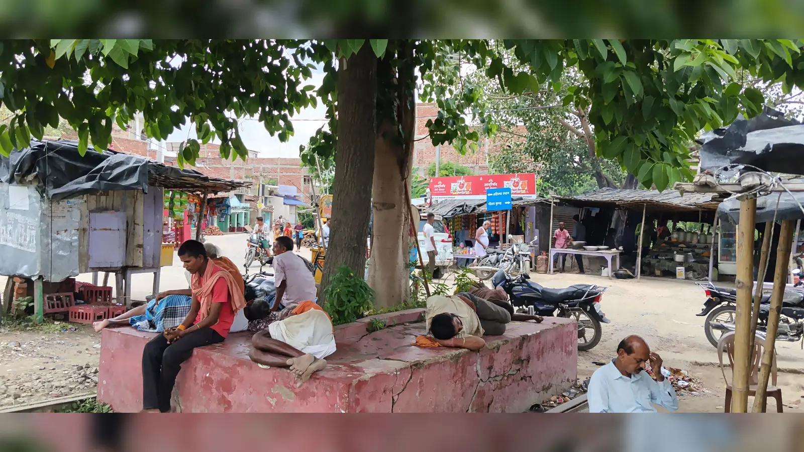 बादलों के बावजूद राहत नहीं: कमतौल बाजार में दोपहर को पसरा सन्नाटा, पेड़ की छांव में ले रहे राहत