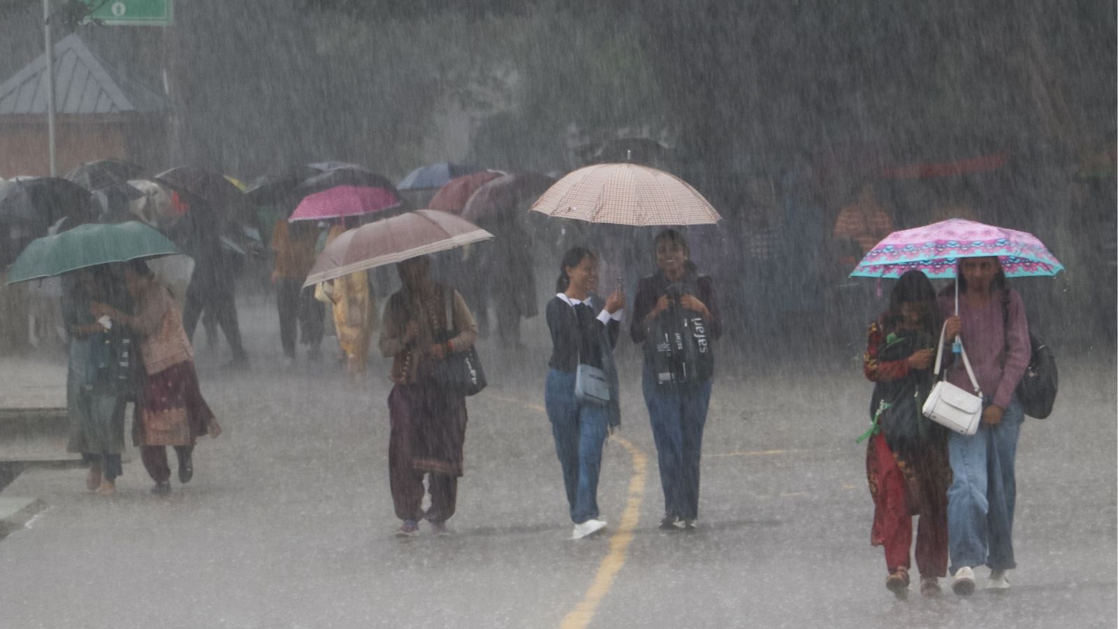 जोरदार बारिश में लोग छाता लेकर चल रहे हैं, फोटो ANI