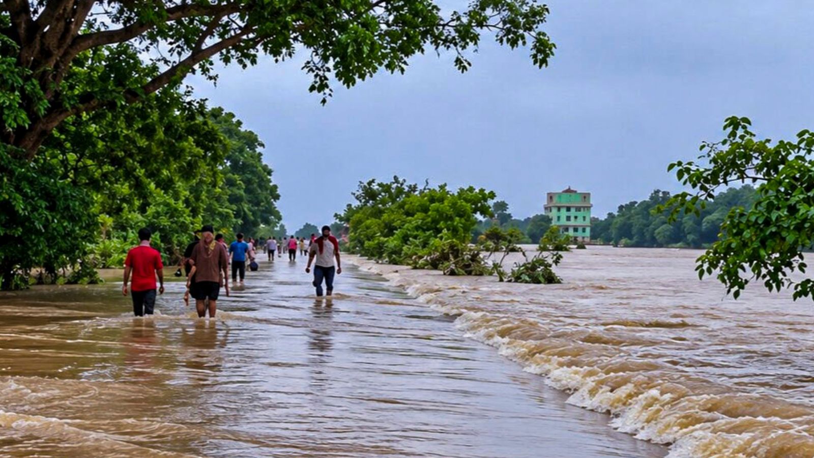 भद्रक में बाढ़ के पानी से पार होते लोग, फोटो पीटीआई