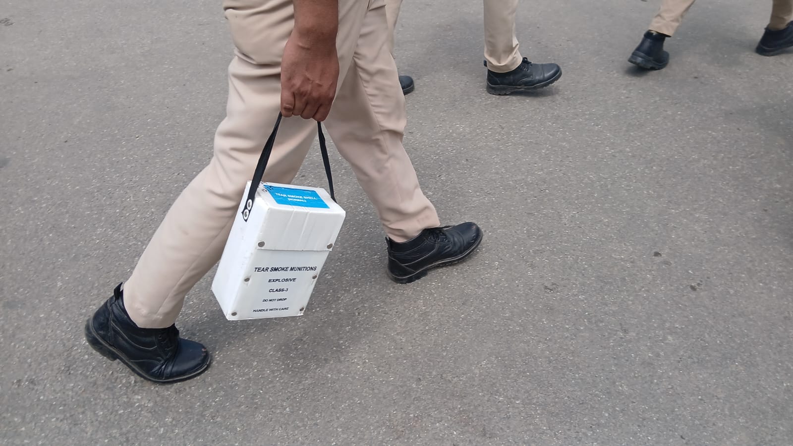 आंसू गैस लेकर जाते पुलिसकर्मी