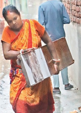 घर में पानी घुसने के बाद सामान निकालती महिला