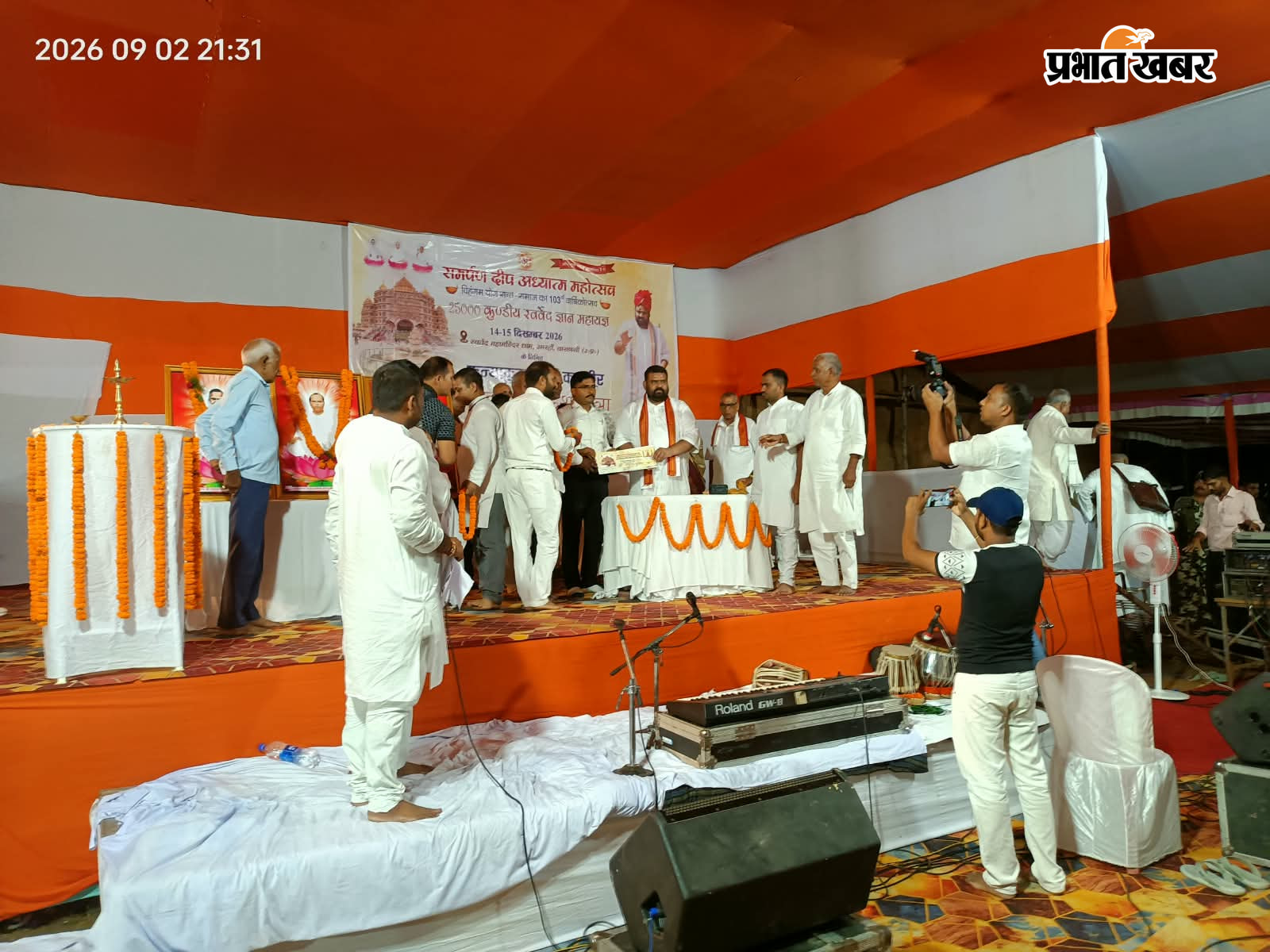 मंच पर महाराज जी बरडीहा बीडीओ को बनारस कार्यक्रम में आने का निमंत्रण देते, मंचासिन महाराज तथा उपस्थित श्रद्धालु | Prabhat Khabar Network