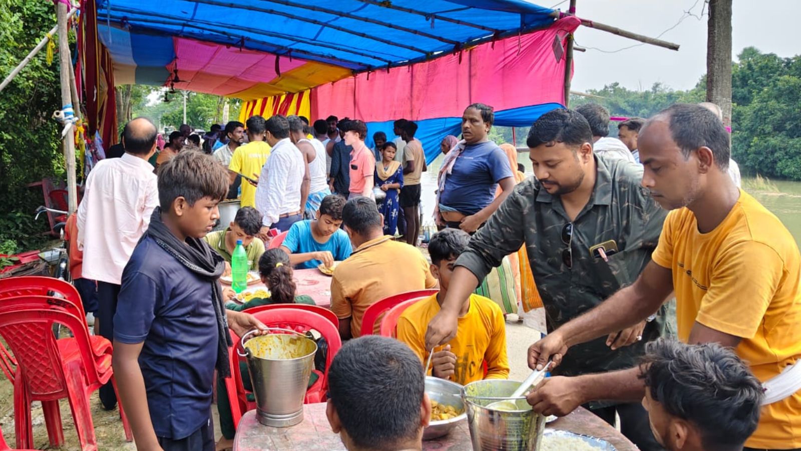 राहत शिविर में बाढ़ पीड़ितों के बीच भोजन परोसते मुखिया प्रतिनिधि.